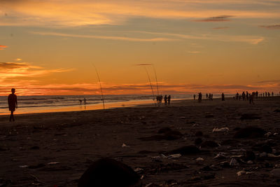 Silhouette people on beach against sky during sunset