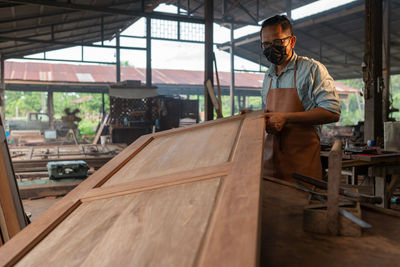 Carpenter wearing mask working at workshop