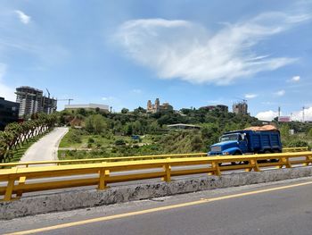 Cars on road by city against sky