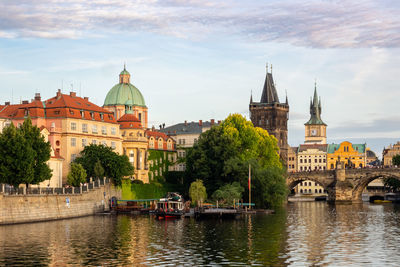 Buildings by river against sky