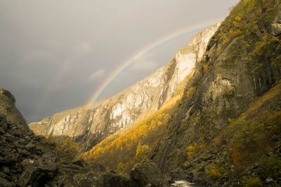 Scenic view of rainbow over mountains against sky