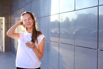 Portrait of smiling young woman standing against window