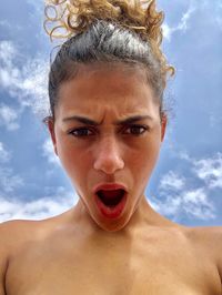 Low angle portrait of topless young woman against sky