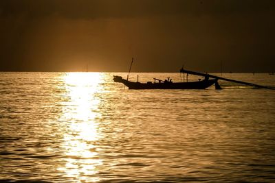 Silhouette sailboat in sea against sky during sunset