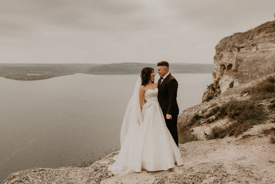 Rear view of bride and groom standing at beach