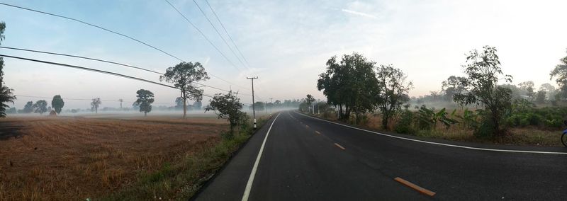 Road by trees against sky