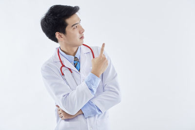 Young man looking away while standing against white background