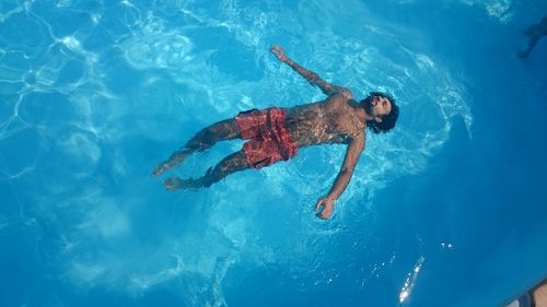 High angle view of shirtless young man swimming in pool