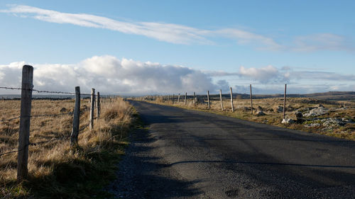 Road amidst field against sky