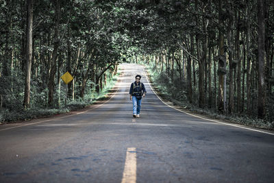 Rear view of man riding bicycle on road