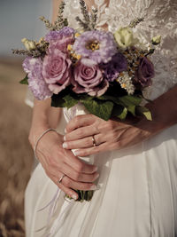 Midsection of bride holding bouquet