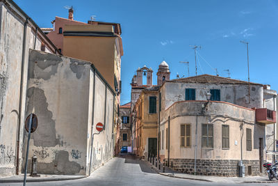 Street amidst buildings against blue sky