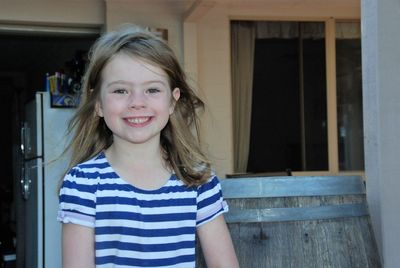 Portrait of smiling girl standing against built structure