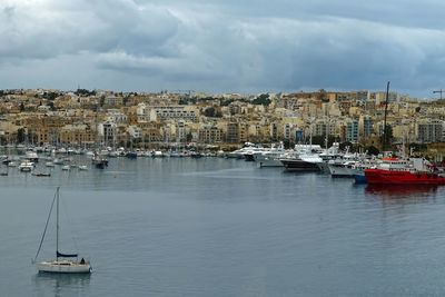 Sailboats moored in sea against sky in city