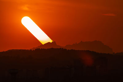 Scenic view of silhouette mountains against orange sky