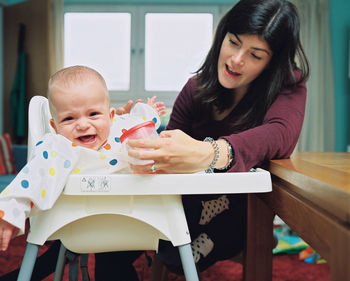 Mother feeding cute son at home