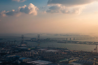 High angle view of commercial dock at harbor against sky during sunset