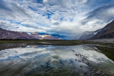 Scenic view of lake by mountains against sky