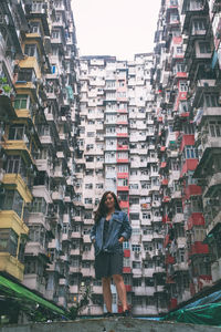 Full length of woman standing against buildings in city