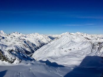 Scenic view of snowcapped mountains against blue sky