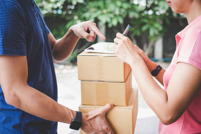 Midsection of delivery man giving cardboard boxes to woman