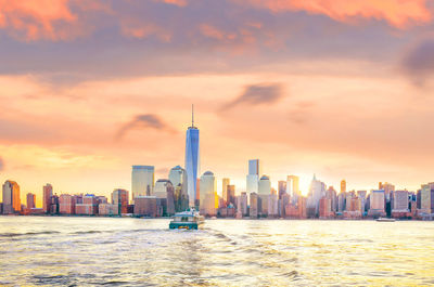 Sea and buildings against sky during sunset