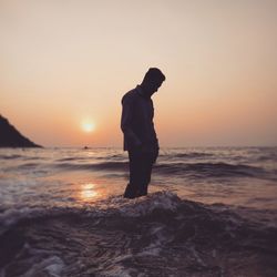 Silhouette of man standing on beach during sunset