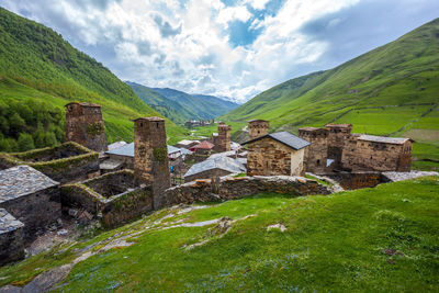 Houses on mountain against cloudy sky