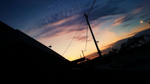 Low angle view of silhouette cranes against sky during sunset