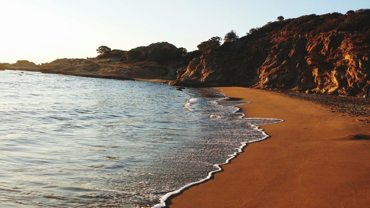 water, tranquil scene, tranquility, scenics, rock - object, beauty in nature, rock formation, nature, clear sky, beach, sea, sky, shore, non-urban scene, rock, idyllic, sand, outdoors, coastline, day