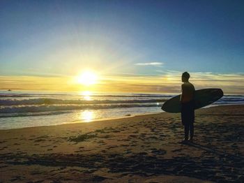 Man standing on beach against sky during sunset