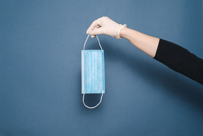 Close-up of hand holding blue background