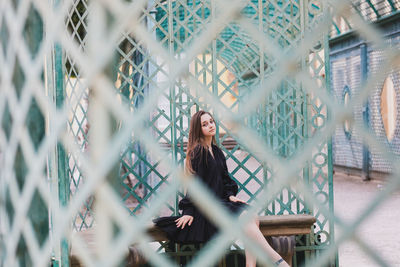 Portrait of woman standing by fence