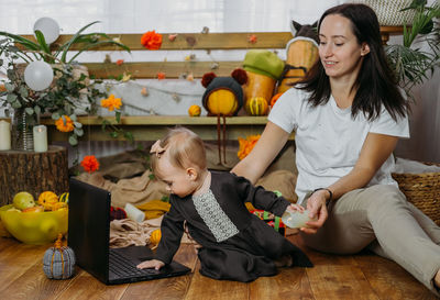 Cheerful mother with daughter looking at laptop at home