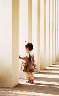 Full length of girl standing in colonnade on sunny day