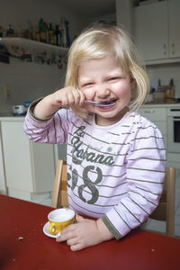 Portrait of a smiling girl holding ice cream at home