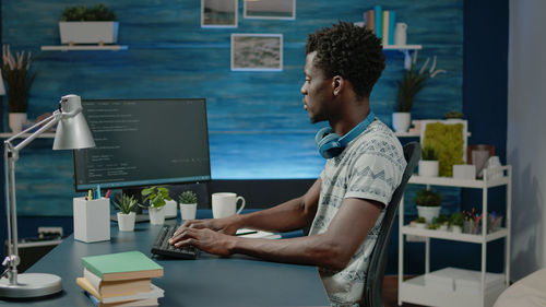 Side view of man using laptop while sitting on table