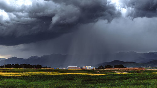 Scenic view of rural landscape against cloudy sky