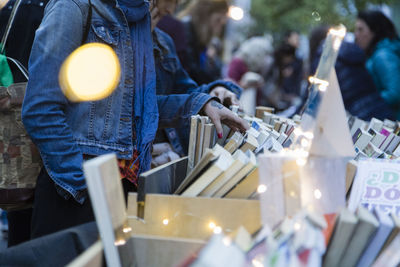 Midsection of woman choosing books at market stall