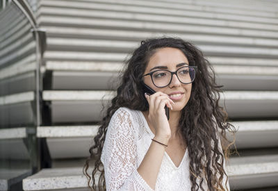 Young woman talking on phone sitting on steps outdoors