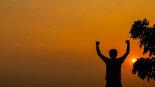 Silhouette man standing against orange sky