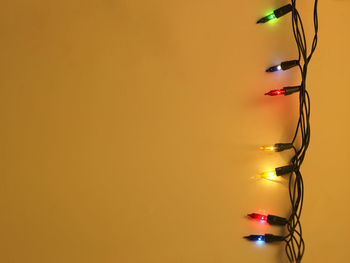 Close-up of illuminated string light over yellow background