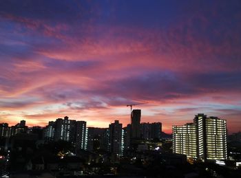 Illuminated buildings in city against sky during sunset