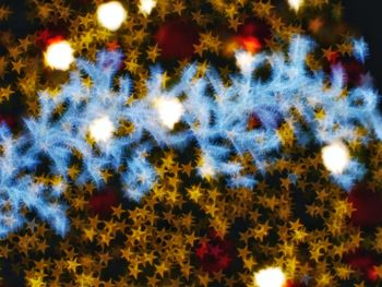 Defocused image of illuminated lights against sky at night