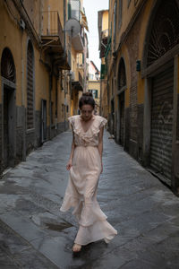 Woman walking on street amidst buildings in city