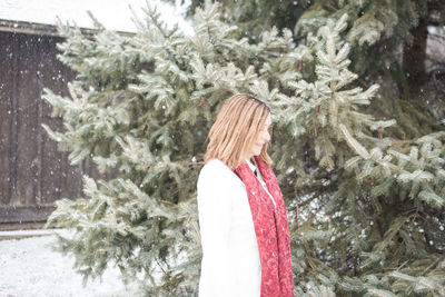 Woman standing on snow covered tree