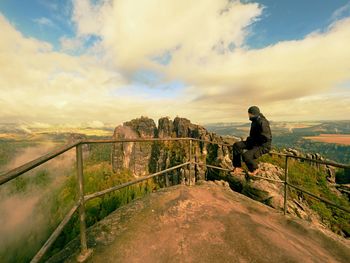 Man standing on railing against sky