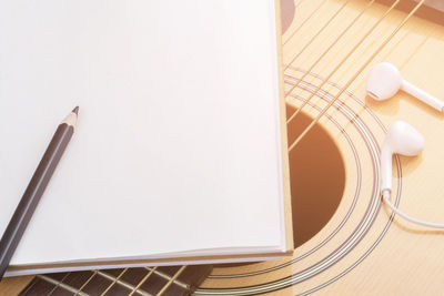 Close-up of pencil and book on guitar