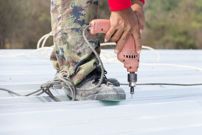 Low section of man drilling in metal