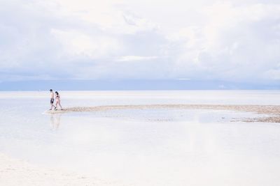 Men on beach against sky